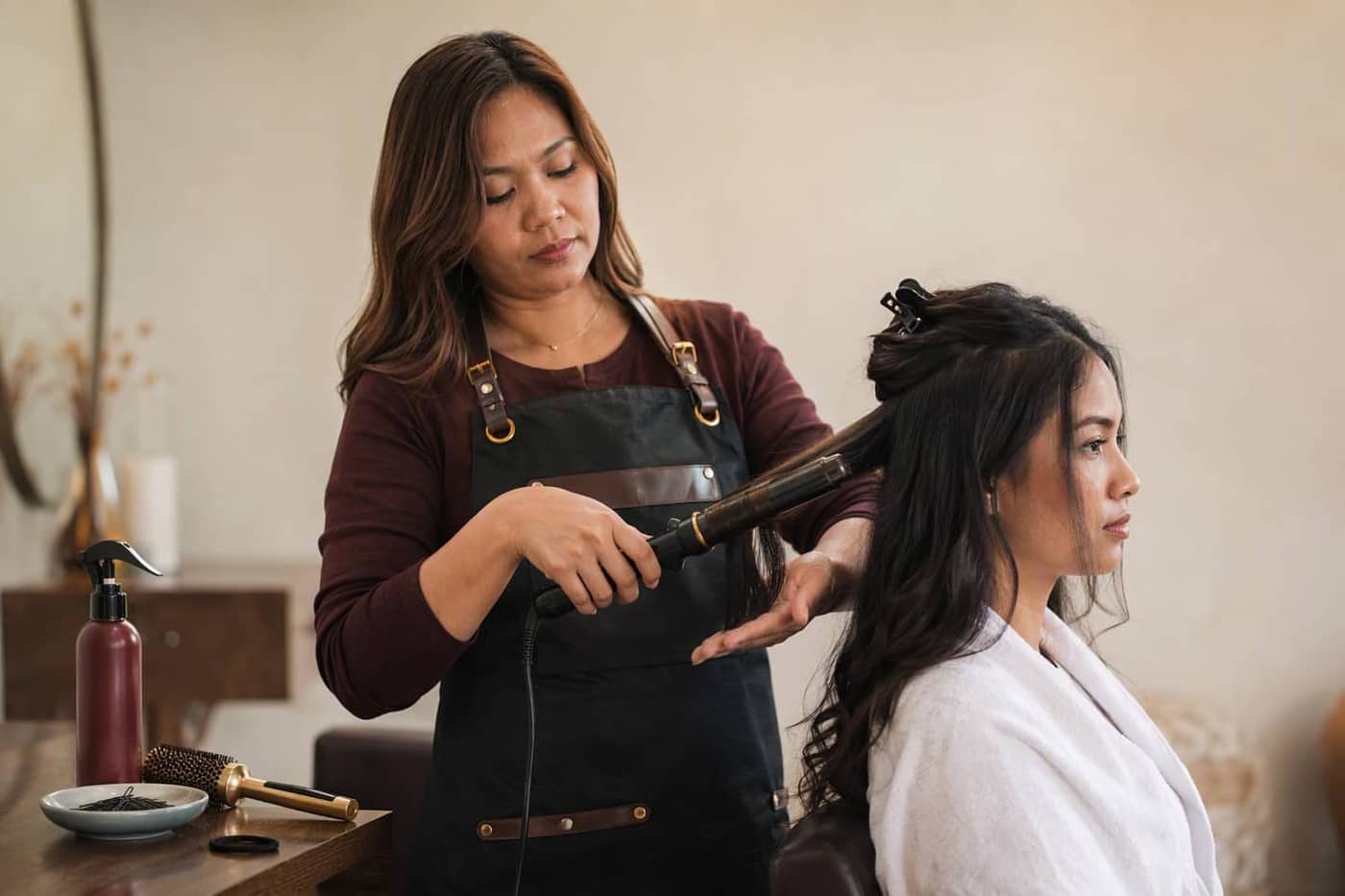 Stylist setting a curl through long hair with a professional wand