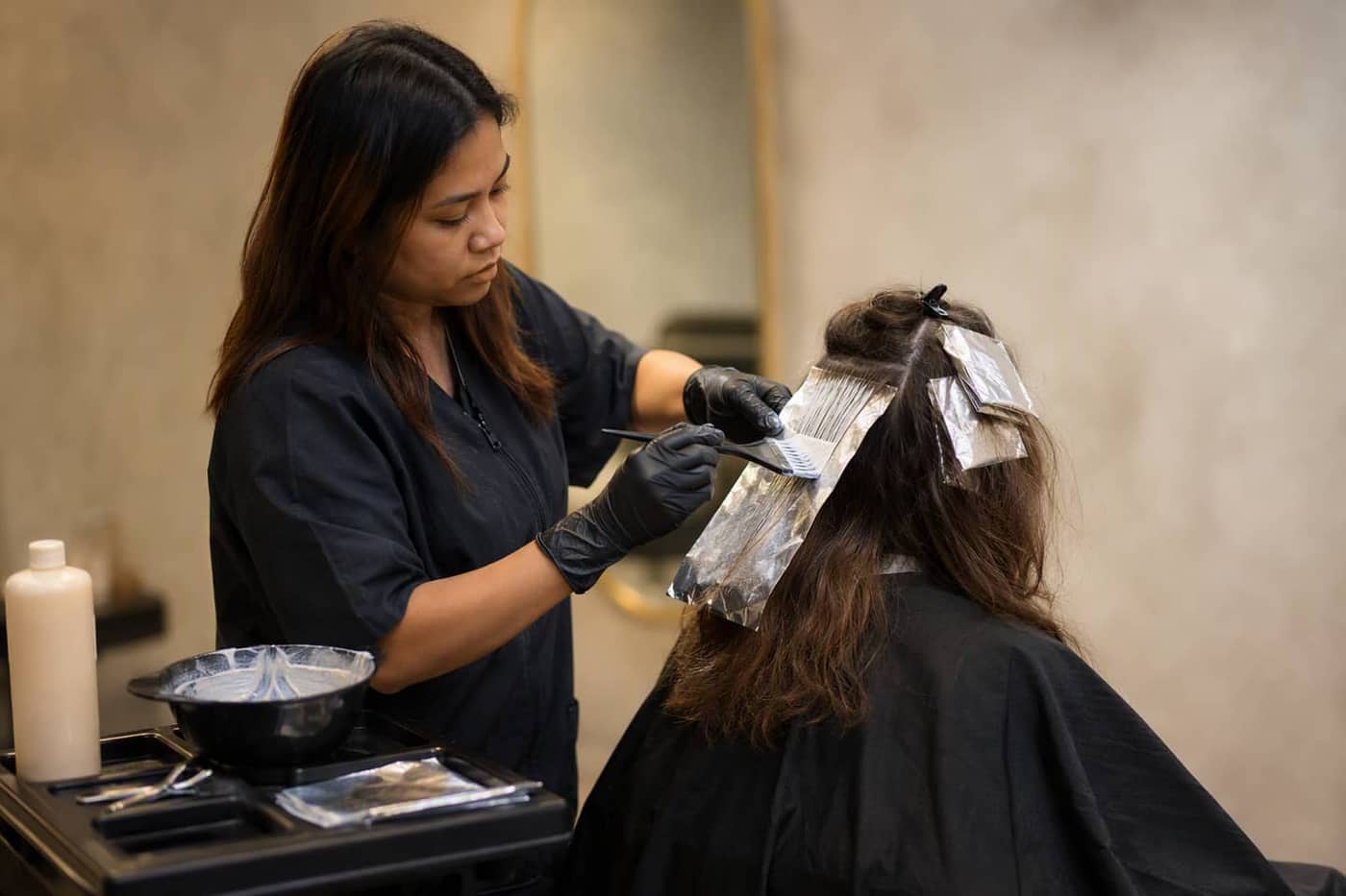 Colorist painting a foil section of hair color in the salon studio